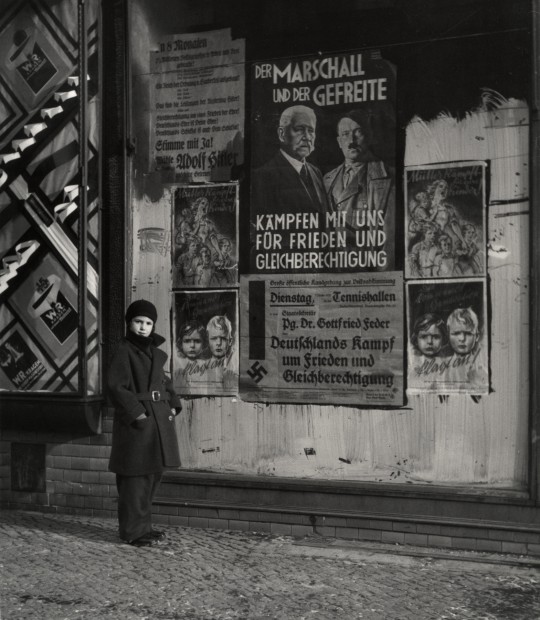 Córka Vishniaca, Mara pozuje przed plakatem wyborczym Hindenburga i Hitlera „The Marshal and the Corporal: Fight with Us for Peace and Equal Rights” Wilmersdorf, Berlin, 1933 © Mara Vishniac Kohn (źródło: dzięki uprzejmości ICP w Nowym Jorku)