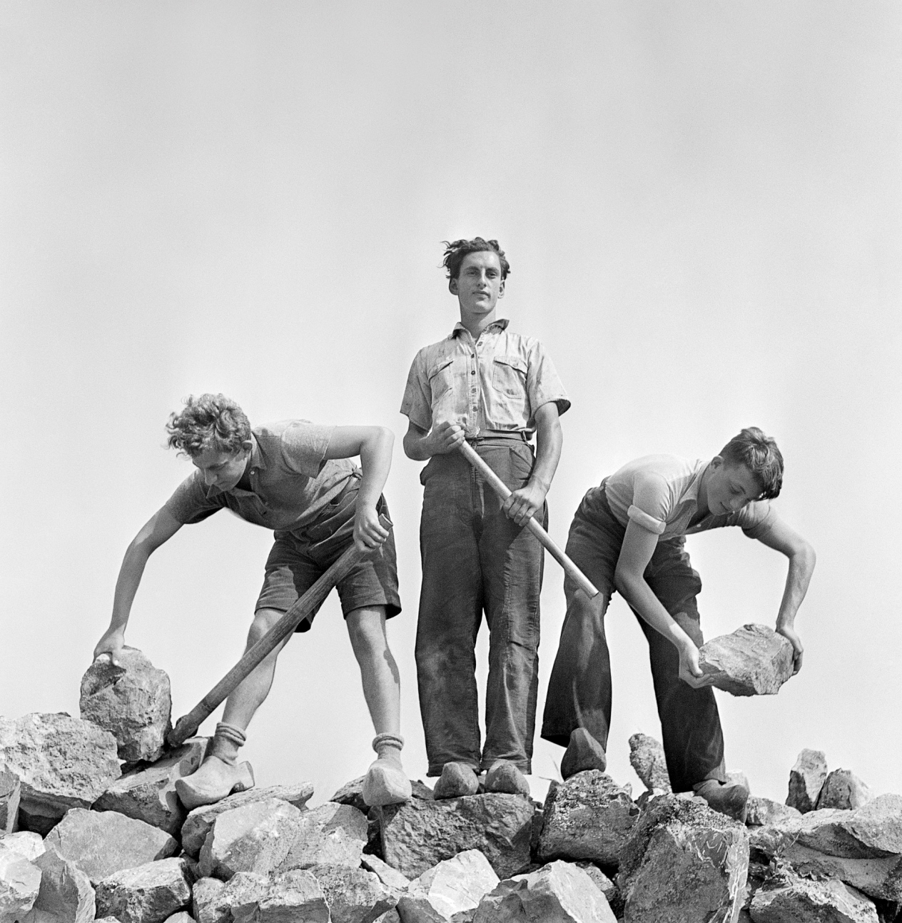[Ernst Kaufmann, center, and unidentified Zionist youth, wearing clogs while learning construction techniques in a quarry, Werkdorp Nieuwesluis, Wieringermeer, The Netherlands], 1939. © Mara Vishniac Kohn, courtesy International Center of Photography (źródło: dzięki uprzejmości International Center of Photography w Nowym Jorku)