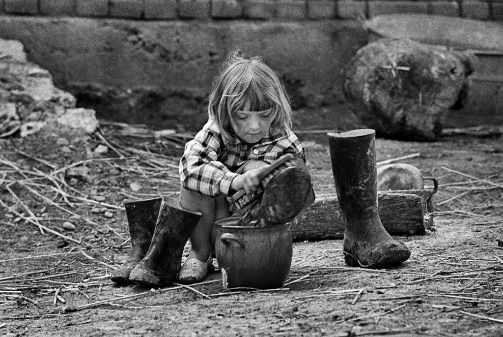 Piekary, Małopolska, 05.1968. Ludzie na wsi, dziewczynka czyści kalosze. Fot. Aleksander Jałosiński (źródło: FORUM)