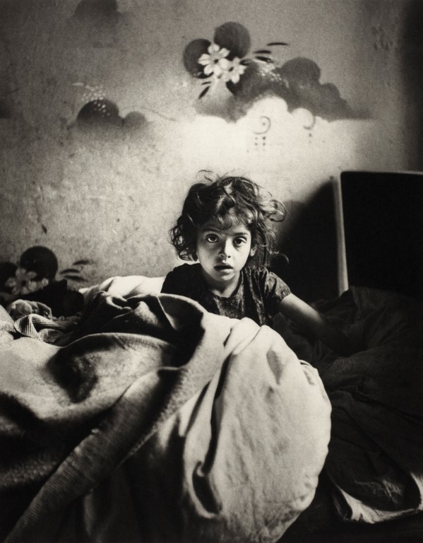 Roman Vishniac „Sara, siedząca w łóżku w mieszkaniu w suterenie, z malowanymi szablonem kwiatami nad głową” Warszawa, ok. 1935-1937 © Mara Vishniac Kohn (źródło: International Center of Photography)