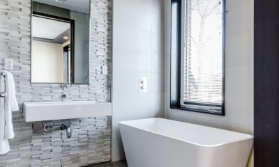 Biała prostokątna wanna w rogu minimalistycznej łazienki